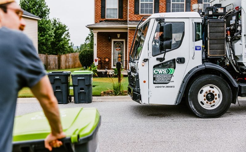 Resident wheels out recycle can to collection truck